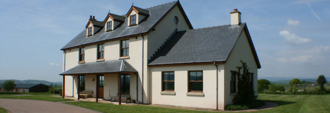 Two-storey cream and grey country house with dormer windows overlooking countryside landscape